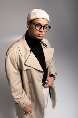 Moda kıyafetli genç adam, basit bir arka plana karşı modaya uygun bir şekilde poz veriyor..