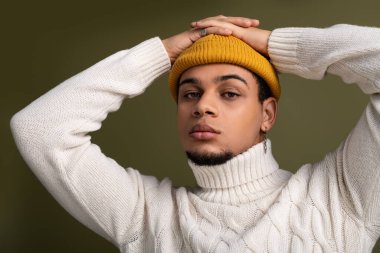 Sade örgü süveter ve parlak bereyle şık genç bir adam kendine güveniyor..
