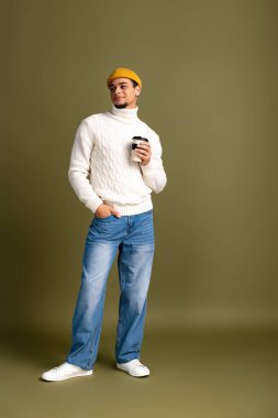 Yakışıklı genç adam elinde kahve fincanı tutarken kendine güvenerek poz veriyor..