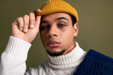 Yakışıklı genç adam rahat bir elbise ve şık bir yerde parlak bir şapka giyer..