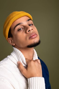 Yakışıklı genç bir adam şık kıyafetlerini basit bir arka plana karşı özgüvenle sergiliyor..