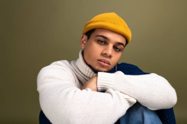 Tarz sahibi genç bir adam rahat bir kıyafetle rahat poz verir. Benzersiz moda anlayışını ve çekiciliğini ön plana çıkarır..