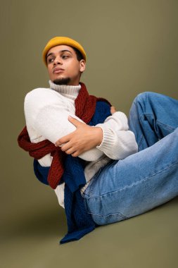 Yakışıklı bir genç adam düşünceli bir şekilde rahat ve rahat bir kıyafetle poz verir..