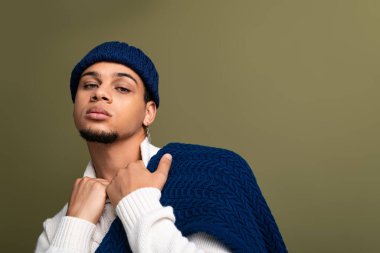 Yakışıklı genç adam şık kıyafetler içinde kendine güvenerek poz veriyor, şık tercihlerinin altını çiziyor..