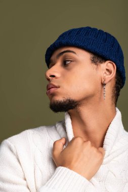 Genç adam kendine güvenen bir şekilde poz veriyor. Yumuşak bir arka plan, ışıl ışıl bir tarz..