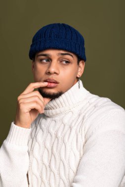 Genç adam örgü süveter ve bereyle özenle poz veriyor..