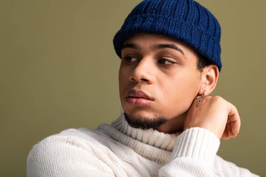 Rahat süveter ve bereli genç adam modern moda anlayışı ve tarzını göstererek zarif bir poz veriyor..