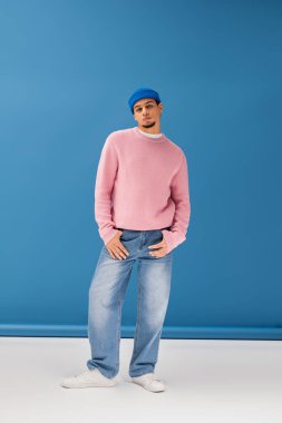 Şık bir genç adam şık kıyafetini sergiliyor, kendine güveni canlı bir sahneye yayılıyor..