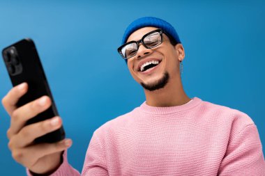 Pembe kazaklı şık bir adam akıllı telefonunu kullanırken gülümsüyor..