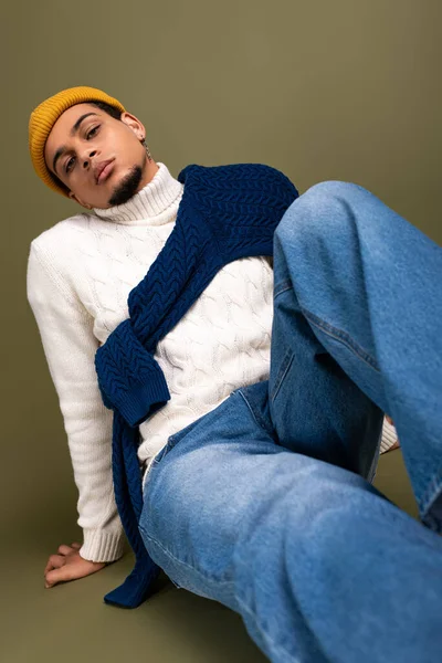 Şık bir genç adam rahat giysiler içinde rahatlar. Parlak bir aksesuarla kendine güvenir..