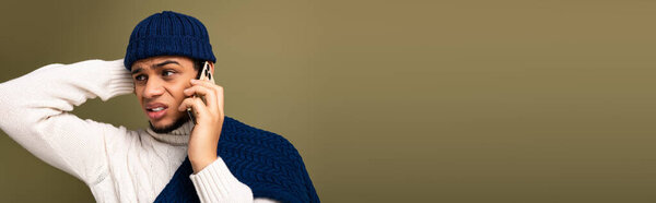 Красивый молодой человек одет модно говорит по телефону с вдумчивым выражением.