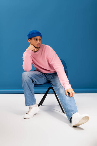 Стильный молодой человек расслабляется в модном наряде, демонстрируя современную моду и индивидуальность.