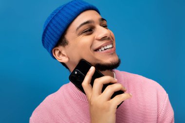 Pembe kazaklı şık bir genç adam akıllı telefonuyla sohbet etmekten hoşlanır..