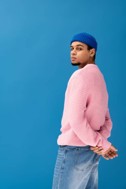 Yakışıklı genç adam kendine güvenerek poz veriyor. Şık, mavi bir arka planı var..