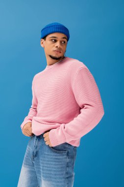 Modayı takip eden genç bir adam kameraya gülümsüyor. Parlak, renkli bir arka plana karşı..