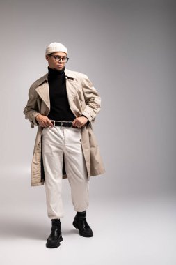 Yakışıklı genç adam şık bir kıyafet giyer. Parlak, tarafsız bir yerde rahatça poz verir..