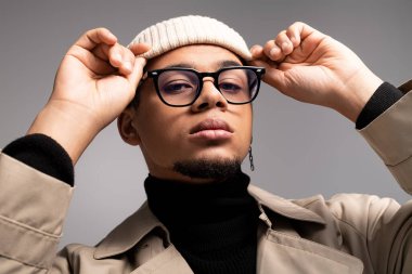 Modaya uygun genç bir adam şık gözlüklerini takar ve kış boyunca güvenli bir şekilde poz verir..