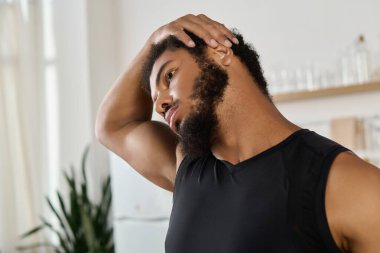 Atletik Afrikalı Amerikalı adam evde esneyerek egzersiz sırasında esnekliğini arttırıyor..