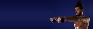 Atletik siyah adam spor yapıyor. Halterleriyle spor yapıyor. Canlı, mavi bir ortamda.