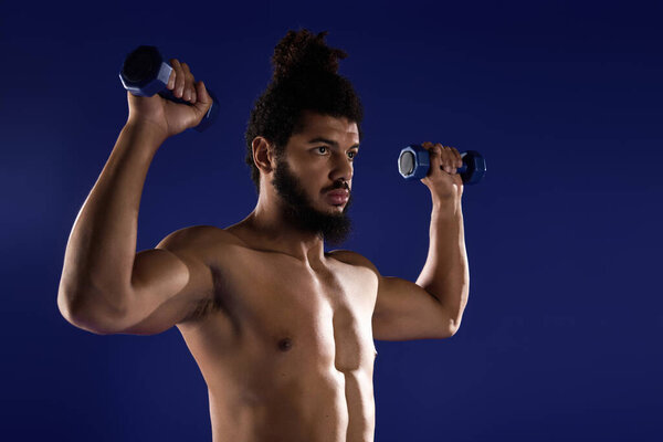 Спортивный человек с вьющимися волосами и бородой демонстрирует силу и сосредоточенность во время тренировки.