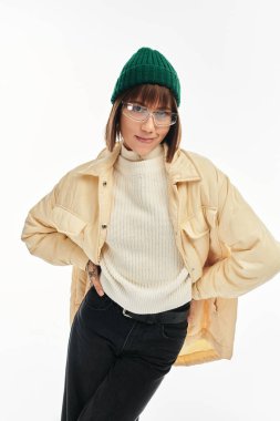 Parlak giyimli genç bir kadın, kendine güvenerek şık bir kış elbisesi içinde poz veriyor..