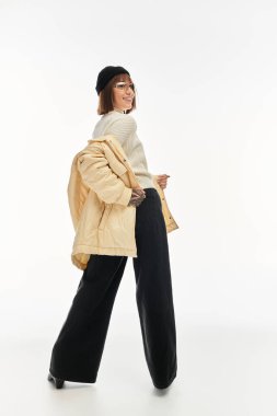 Güzel, genç bir kadın kendine güvenerek poz veriyor. Şık kış kıyafetleri içinde, mutluluk saçıyor..