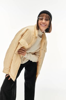 Parlak bir stüdyoda, genç bir kadın modern moda neşesini somutlaştıran şık kıyafetini sergiliyor..