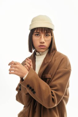 Tarz sahibi genç bir kadın, minimalist bir geçmişe karşı özgüvenle poz verir..