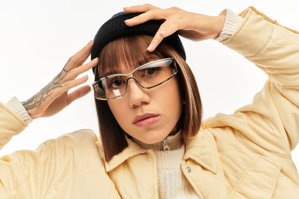 In a chic setting, a young woman poses confidently in stylish attire and accessories.