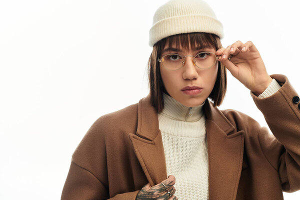 Модная молодая женщина надевает шикарную зимнюю одежду, излучая уверенность и стиль в ателье.