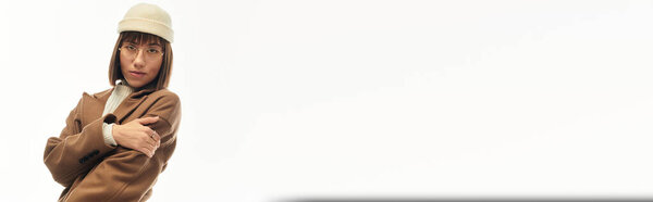 Молодая женщина демонстрирует стильный наряд, излучая элегантность и уверенность в минималистской обстановке.