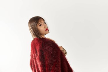 Tarz sahibi genç bir kadın dikkat çekmeden dikkat çekmek için dikkat çekici kırmızı bir ceketle rahatlıkla poz veriyor..