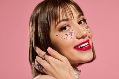 Parlak gülümseyen genç kadın saçlarına neşeyle dokunurken şık elbisesini sergiliyor..