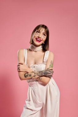 Güzel bir genç kadın şık kıyafetler giyer ve kendine güveni canlı pembe bir arka planda yayar..