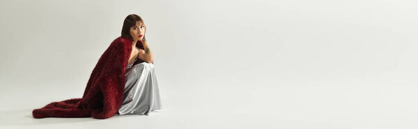 Young woman dressed in fashionable attire poses gracefully, exuding confidence and style.