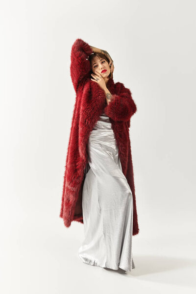 A young woman in a chic red coat and silver dress exudes confidence.