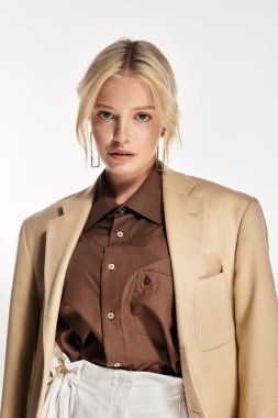 Güzel, genç, sarışın bir kadın, beyaz bir stüdyoda kışlık kıyafetle güven içinde poz veriyor..