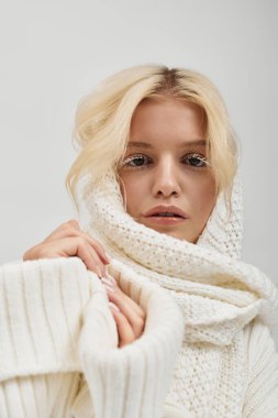 Beyaz kirpikli çekici genç bir kadın rahat örülmüş bir süveter içinde poz veriyor..