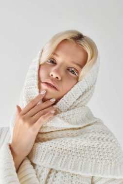 Beyaz kirpikli genç bir kadın kalın bir süveter giyer ve davetkar bir atmosfer yaratır..