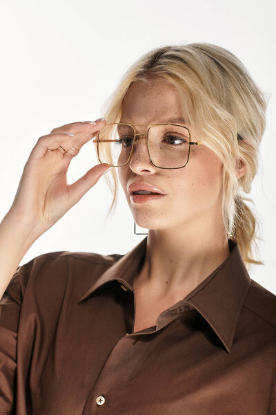 Красивая молодая блондинка элегантно позирует в модном зимнем наряде на белом фоне.