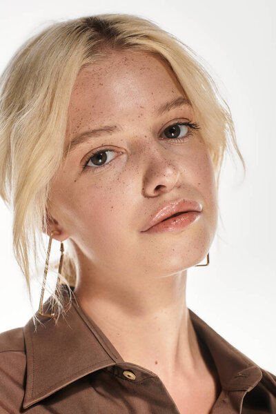 A young blonde woman poses confidently in a chic winter outfit on a white background.