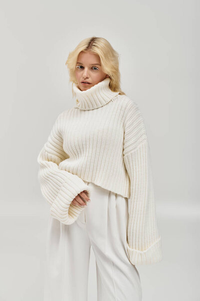 A beautiful young woman poses in a cozy knitted sweater, showcasing winter style in a studio.