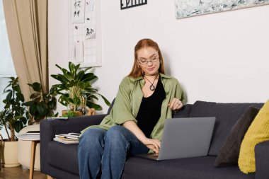 Genç bir kadın rahat bir şekilde evinde oturuyor ve laptopuyla çalışıyor..