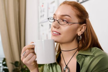 Genç bir kadın sıcak ve sakin bir şekilde evinde çayını yudumluyor..