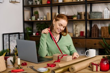 Sıcak ve davetkar bir evde, genç bir kadın bayram süsleriyle çevrili bir hediyeyi neşeyle sarar..