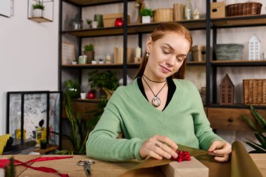 Genç bir kadın, bitkiler ve sıcak ev dekorasyonu ile çevrili iken sanattan zevk alır..