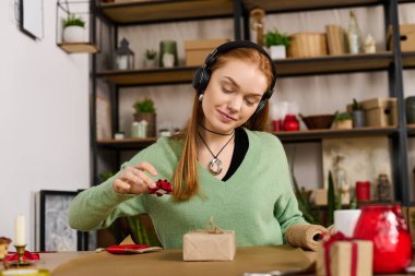 Genç bir kadın sıcak ve davetkar bir ev ortamında hediye paketlemekten zevk alır..