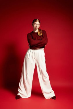 Kızıl saçlı bir kadın, kış modası için rahat bir süveter ve şık bir pantolon mankeni..