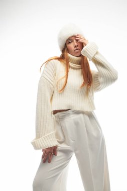 Genç bir kızıl, şık bir kışın tadını çıkarır. Kürk şapkası ve rahat bir süveter giyer..