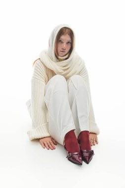 Genç kızıl saçlı bir kadın, rahat bir kazakla kış modasına modellik yapıyor.